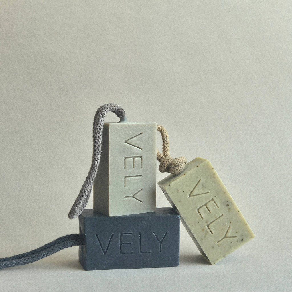 Three bars of VELY soap on a gray background