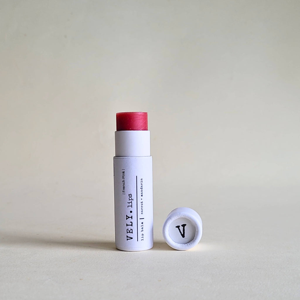 French Pink reddish  tinted lip balm in a paper tube with cap with VELY branding on a beige background