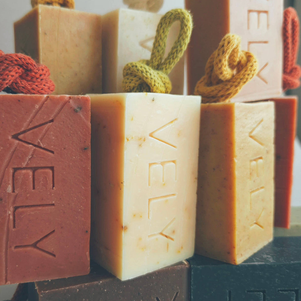 Assorted bars of soap with 'VELY' branding on a neutral background