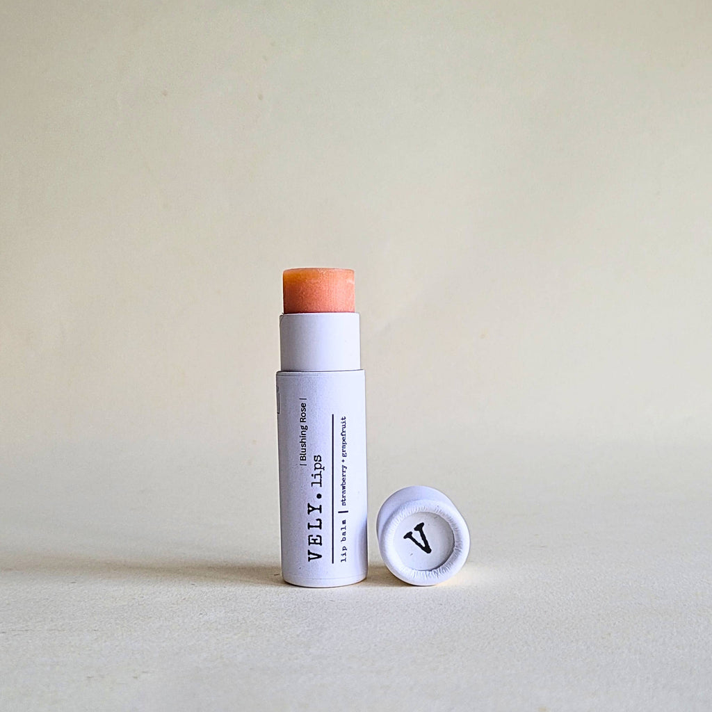 Blushing rose lip balm with cap in compostable packaging on a beige background