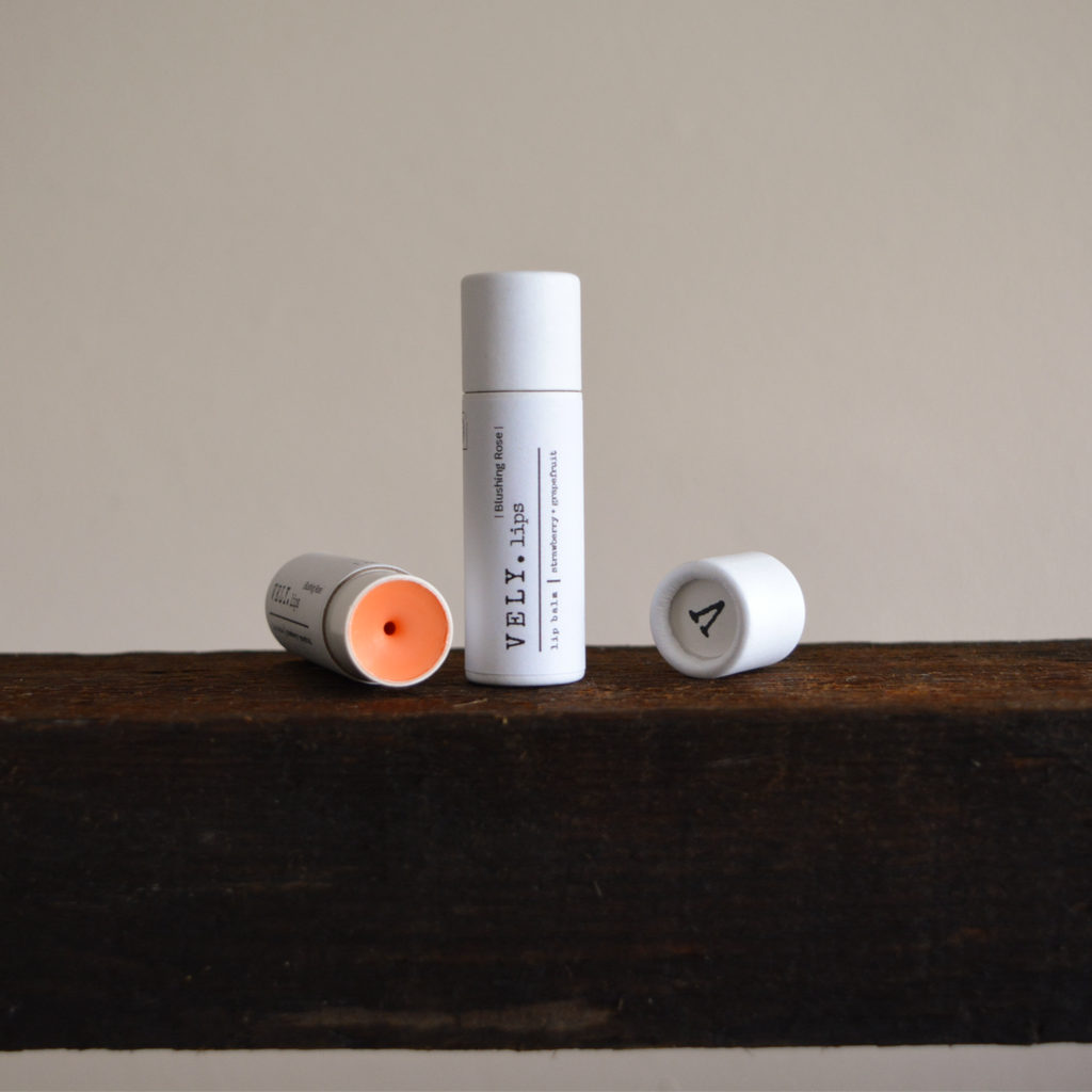 Two lip balm tubes on a wooden surface with a neutral background