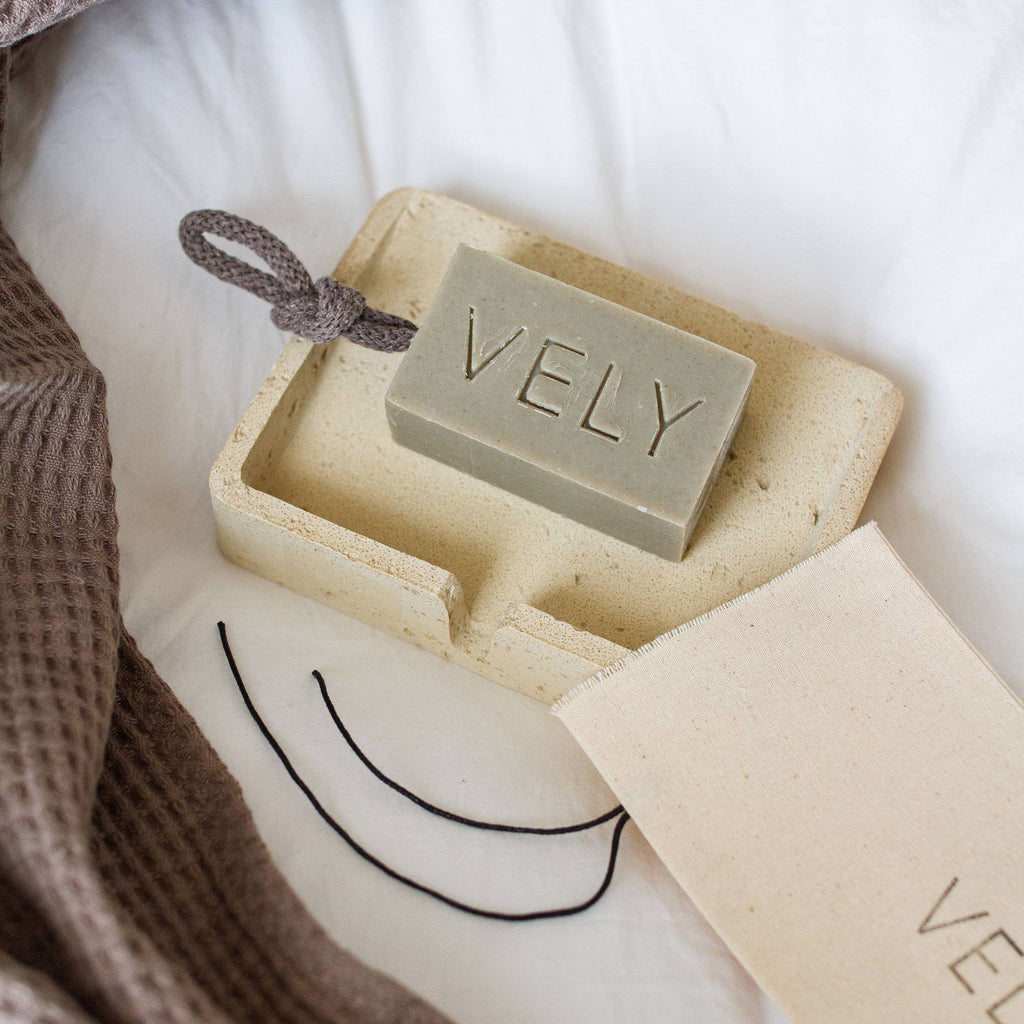 Bar of soap with 'VELY' branding in a box on a soft surface