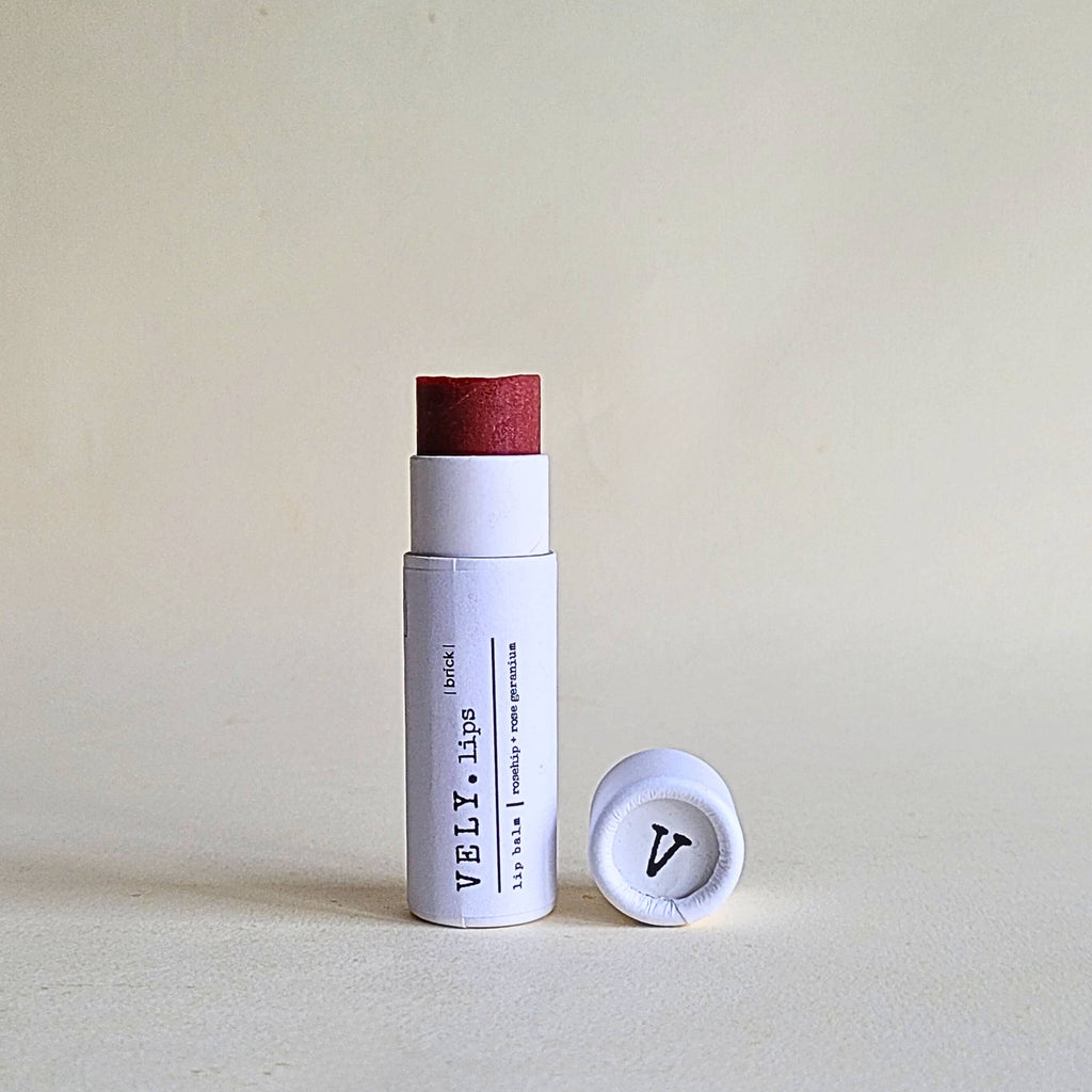 Red brick deep red tinted lip balm  in white colour cardboard tube on a beige background